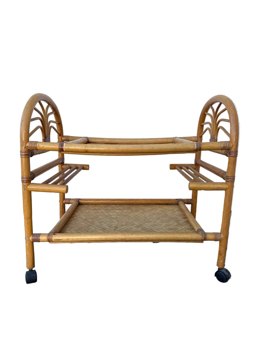 Rattan bar cart against a tiled wall and concrete floor.